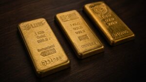 Three one-kilogram Swiss gold bars stamped 999.9 purity on a dark walnut surface