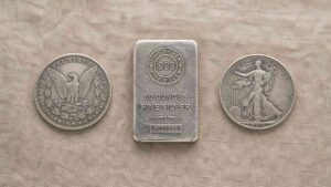 Silver bullion comparison: Morgan dollar coin, 10-ounce .999 fine silver bar, and Walking Liberty half dollar on linen surface