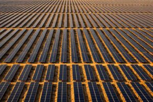 Aerial view of a large-scale solar farm stretching to the horizon at golden hour