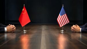 US-China summit negotiators face each other across a conference table with Chinese and American flags — a moment that will shape gold and silver prices