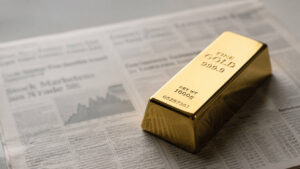 Gold bar resting on financial newspaper — gold price structural bid holds firm amid jobs data and deficit news