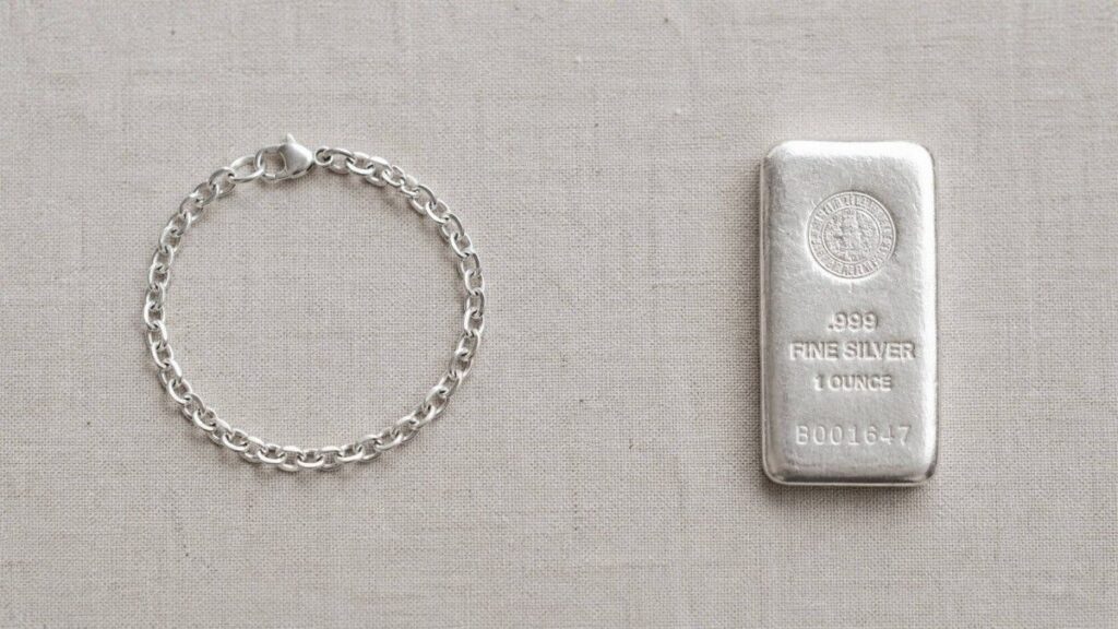 Silver bracelet and a 1-ounce .999 fine silver bullion bar side by side on a linen surface — illustrating the difference between silver jewelry and silver bullion as investments