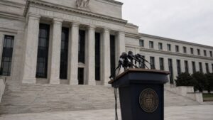 Empty Federal Reserve press conference lectern with clustered microphones outside the Eccles Building in Washington D.C., illustrating the Fed's decision to drop forward guidance — and what fed forward guidance gold holders need to understand
