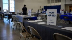 Empty job fair with a Now Hiring sign, illustrating the gold price unemployment rate story: fewer people searching for work drove June's unemployment rate lower, not stronger hiring.