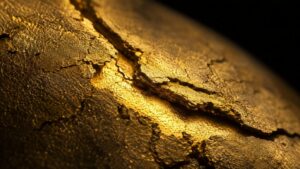 Gold surface with deep cracks revealing luminous gold beneath — gold silver market correction 2026