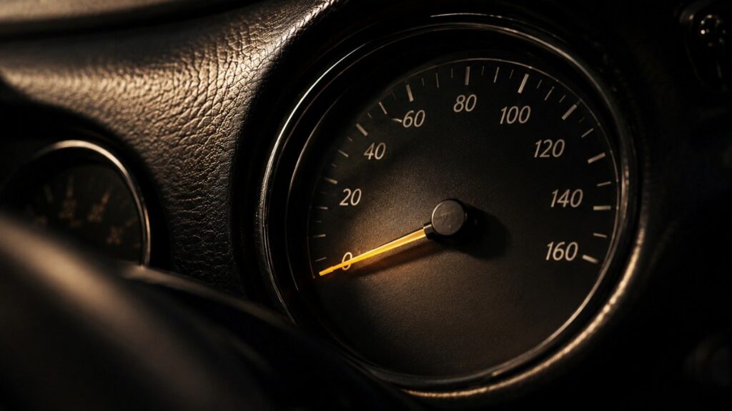 Speedometer needle resting near zero — velocity of money chart showing how slowly dollars are circulating in the economy