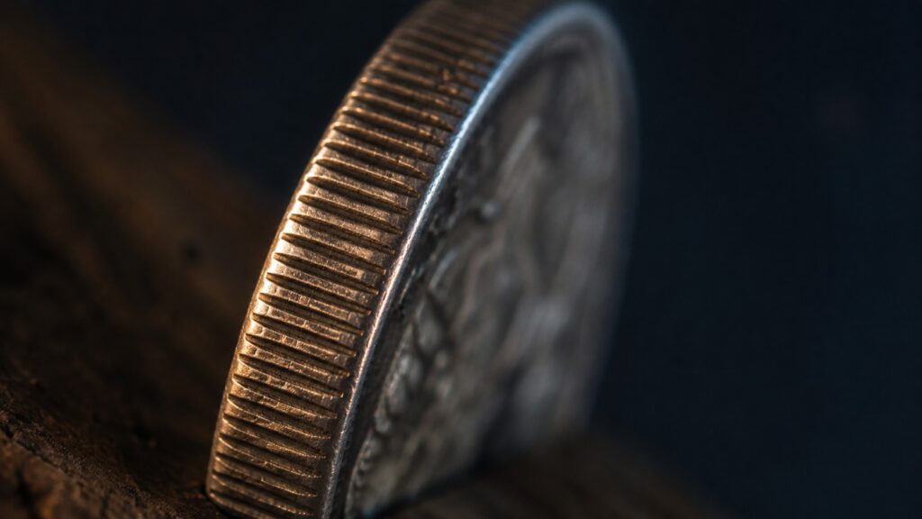 Macro close-up of a coin's milled reeded edge on dark wood, illustrating what is sound money in physical form