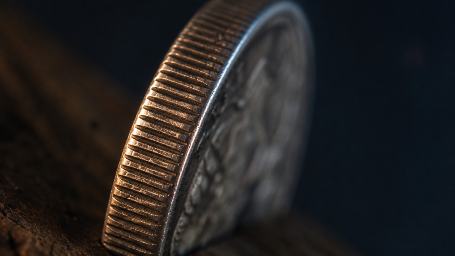 Macro close-up of a coin's milled reeded edge on dark wood, illustrating what is sound money in physical form