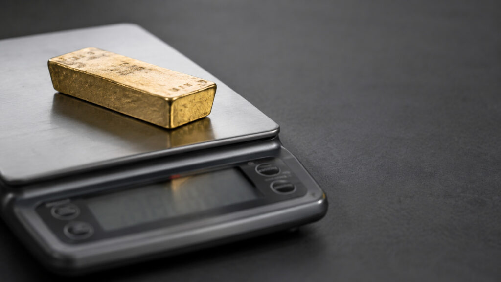 How much is a gold bar worth: a gold bar on a precision scale showing its weight in grams, the figure that sets its metal value.