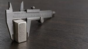 A precision caliper measuring a single silver bullion bar, illustrating the narrowing gap between spot silver and UBS's stated price forecast
